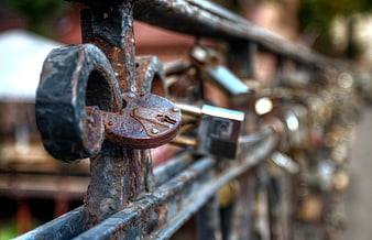 Rusty padlock on bridge railing with blurred background