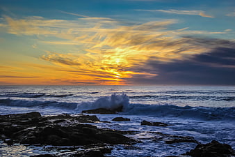 Dramatic Sunset Over Rocky Ocean Coast with Crashing Waves
