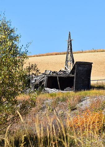 Dilapidated wooden windmill in golden rural field