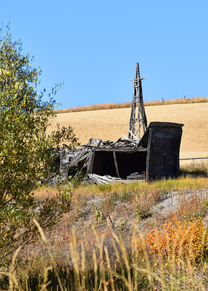 Dilapidated wooden windmill in golden rural field