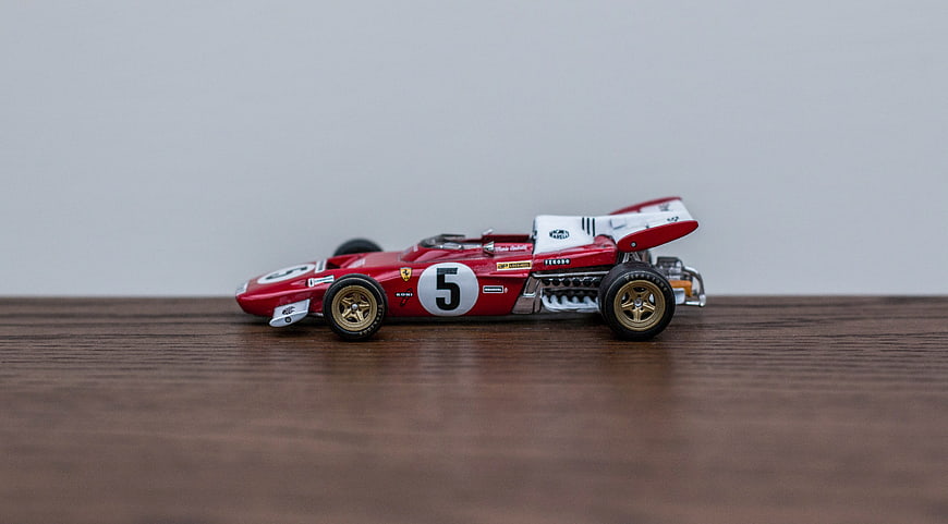 Red vintage die-cast Formula 1 race car model on wood