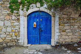 Vibrant Blue Arched Wooden Door Set In Rustic Stone Wall