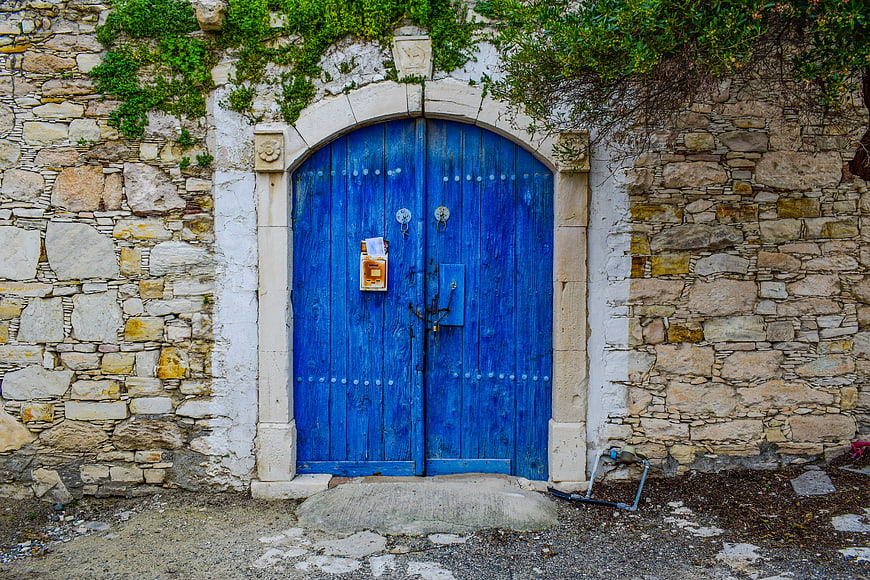 Vibrant Blue Arched Wooden Door Set In Rustic Stone Wall