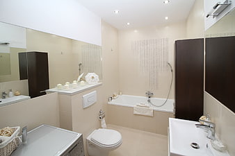 Modern beige bathroom interior with bathtub and washing machine