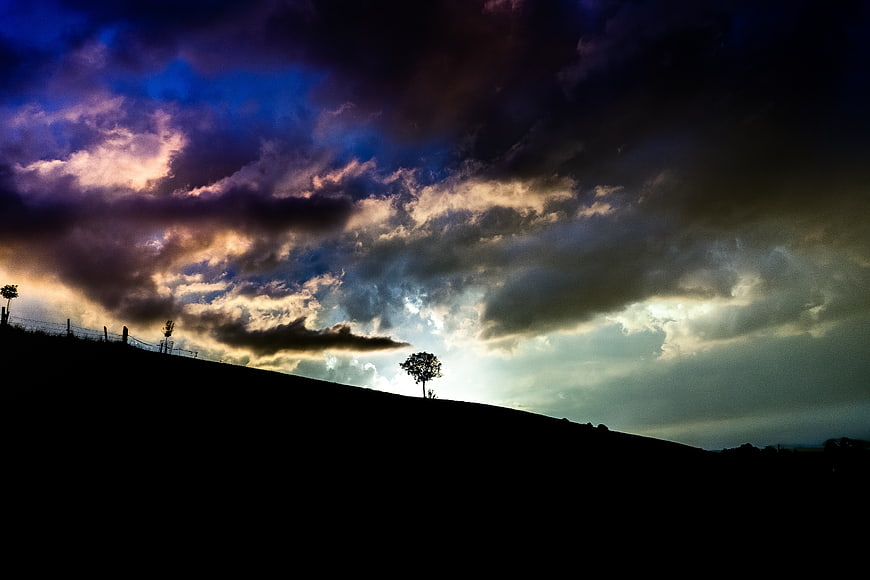 Dramatic Stormy Sky Over Silhouetted Hill Landscape