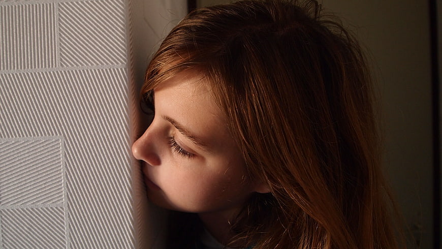Close-up of woman with eyes closed leaning against textured wall