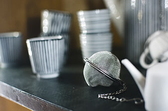 Close-up of metal tea infuser on dark counter
