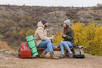 Happy hiking couple resting on bench with autumn scenery