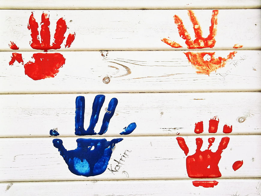 Colorful child handprints painted on white wooden planks
