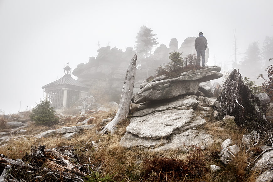 Man standing on rocky mountain peak in foggy weather