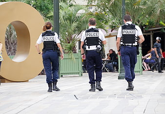 Three police officers walking away in urban plaza
