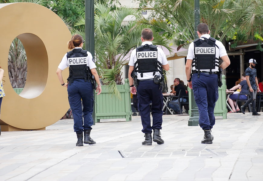 Three police officers walking away in urban plaza