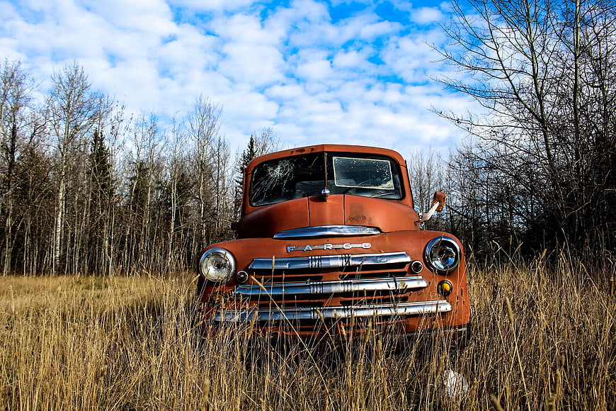 Rusty vintage Fargo truck abandoned in tall grass field