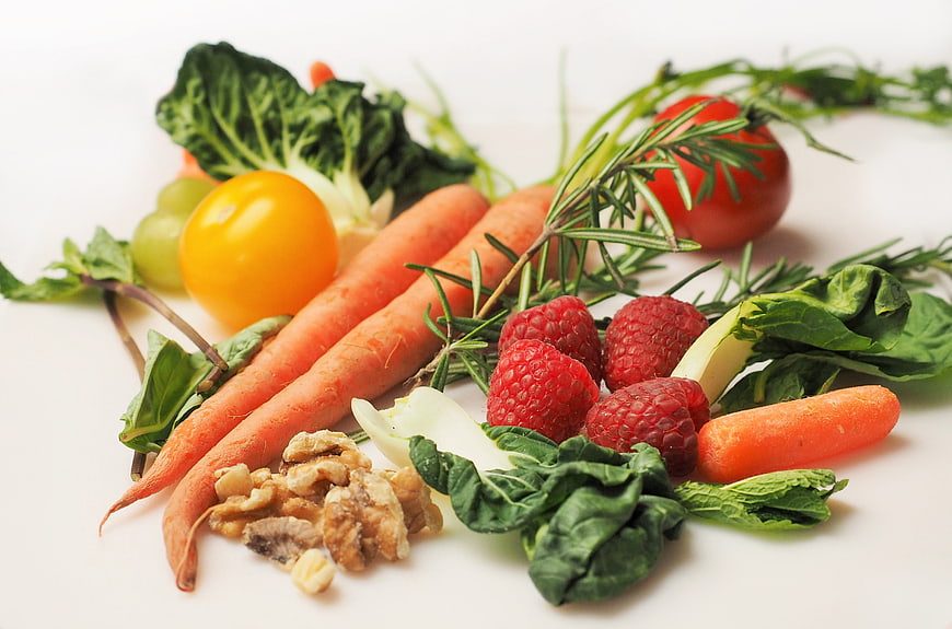 Fresh organic vegetables, fruits, and nuts on white background
