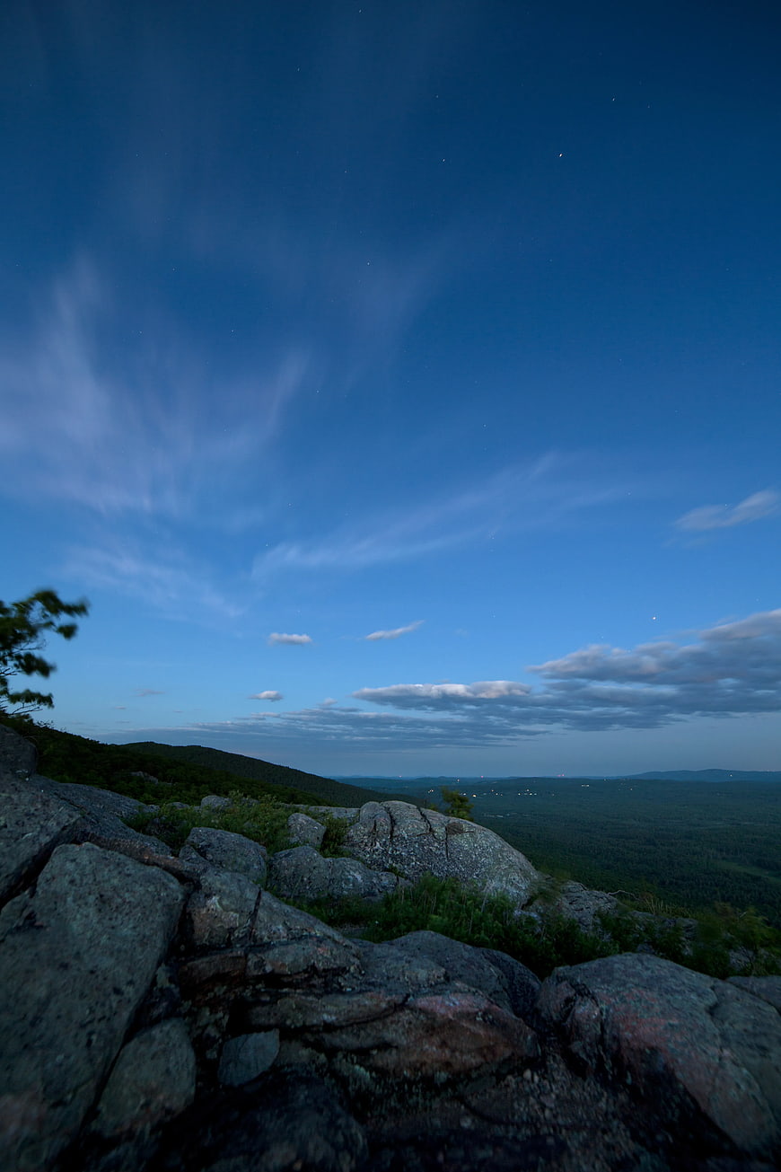 Blue Hour Mountain Landscape with Rocky Foreground and Distant City Lights