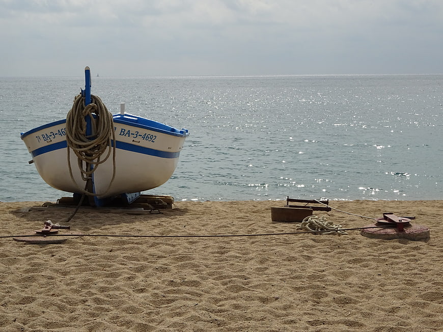 White and blue fishing boat resting on sandy beach