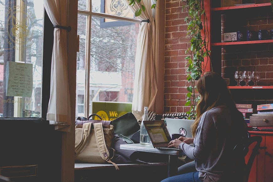Woman working on laptop in cozy cafe by window