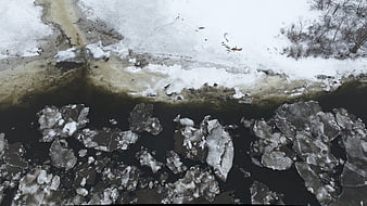 Aerial view of frozen river with broken ice chunks in winter