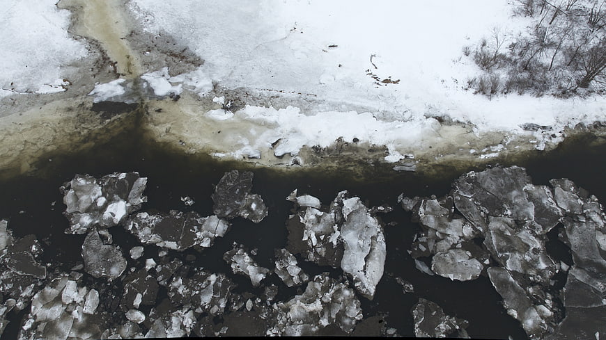 Aerial view of frozen river with broken ice chunks in winter