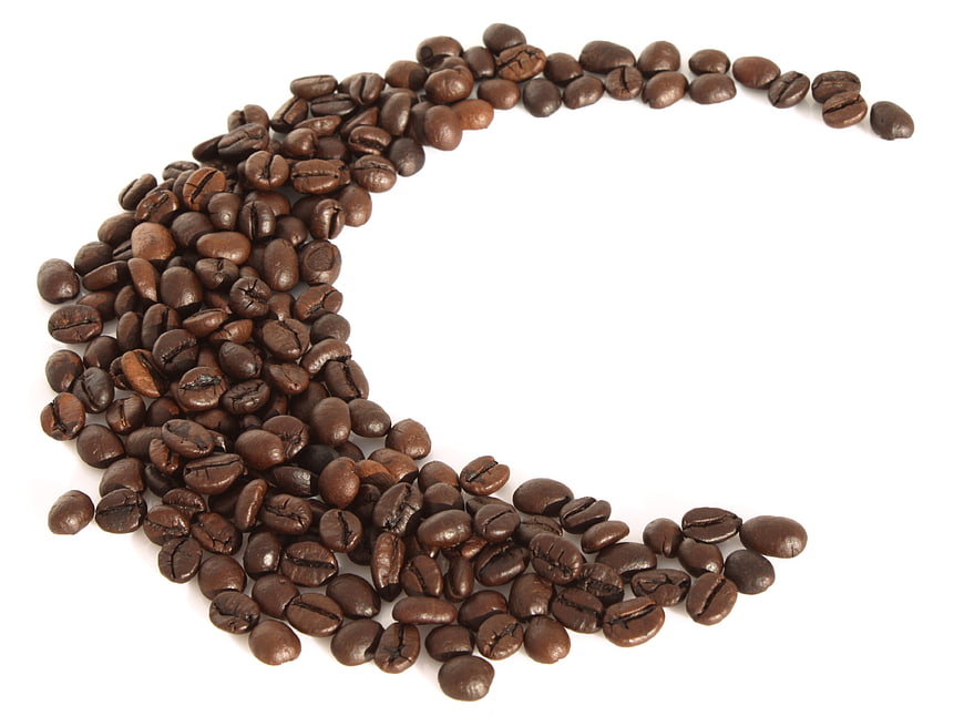 Coffee beans arranged in a crescent shape on white background