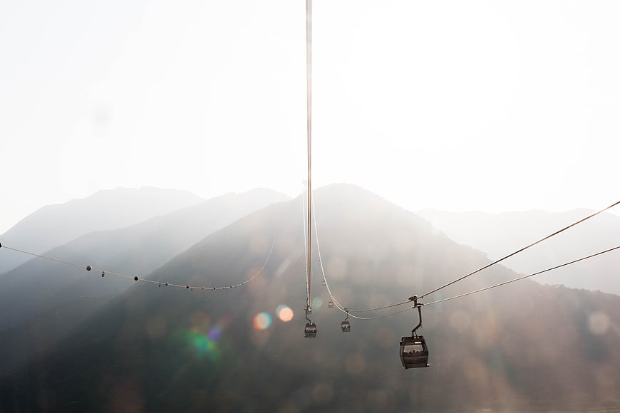 Cable cars ascending misty mountain ridge at sunrise
