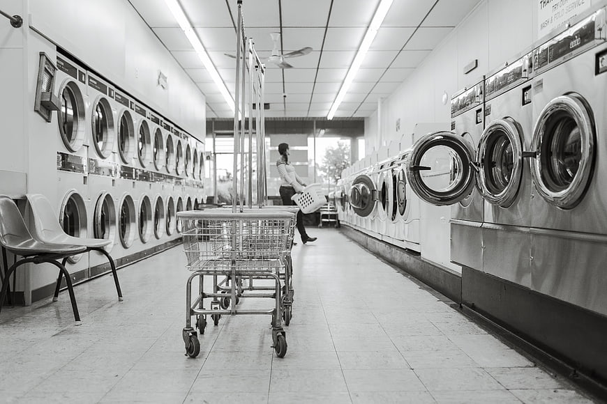 Black and white laundromat interior with washing machines and cart