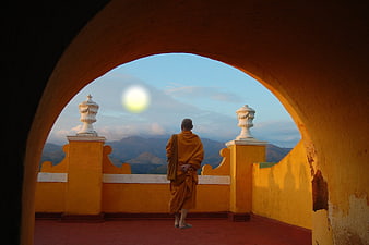 Buddhist monk standing on a terrace at sunset