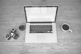 Black and white flat lay of laptop, vintage camera, and coffee