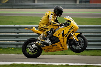 Yellow racing motorcycle performing a wheelie on a race track