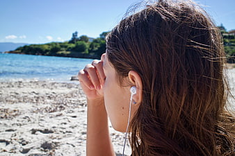 Woman listening to music on a sunny beach with earphones