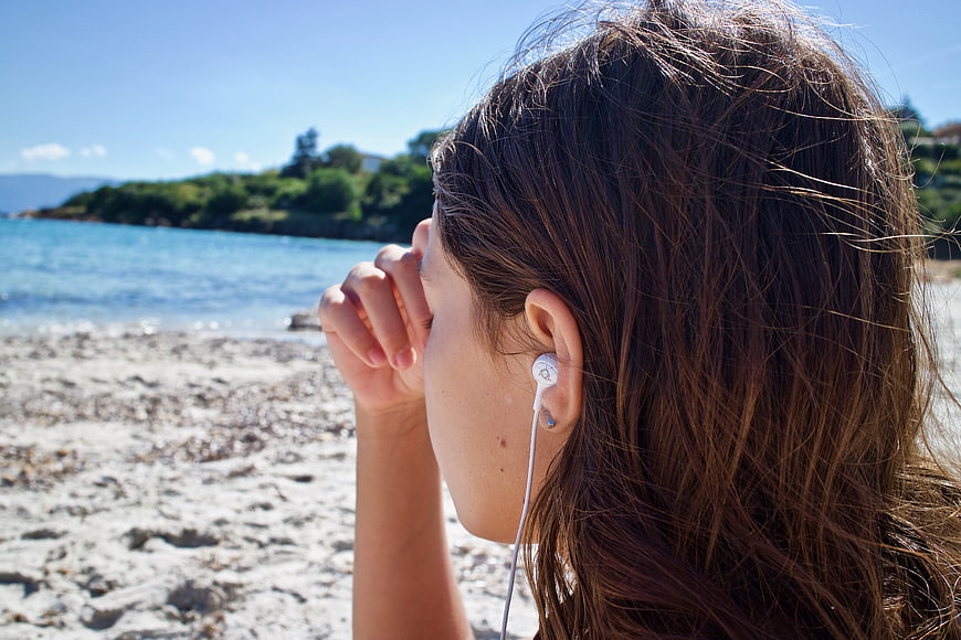 Woman listening to music on a sunny beach with earphones