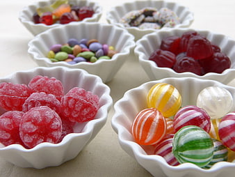 Assorted colorful candies in white fluted bowls