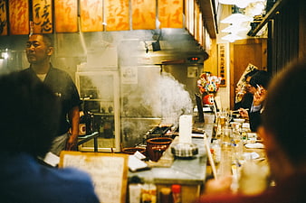 Chef cooking at a busy Japanese restaurant counter with steam