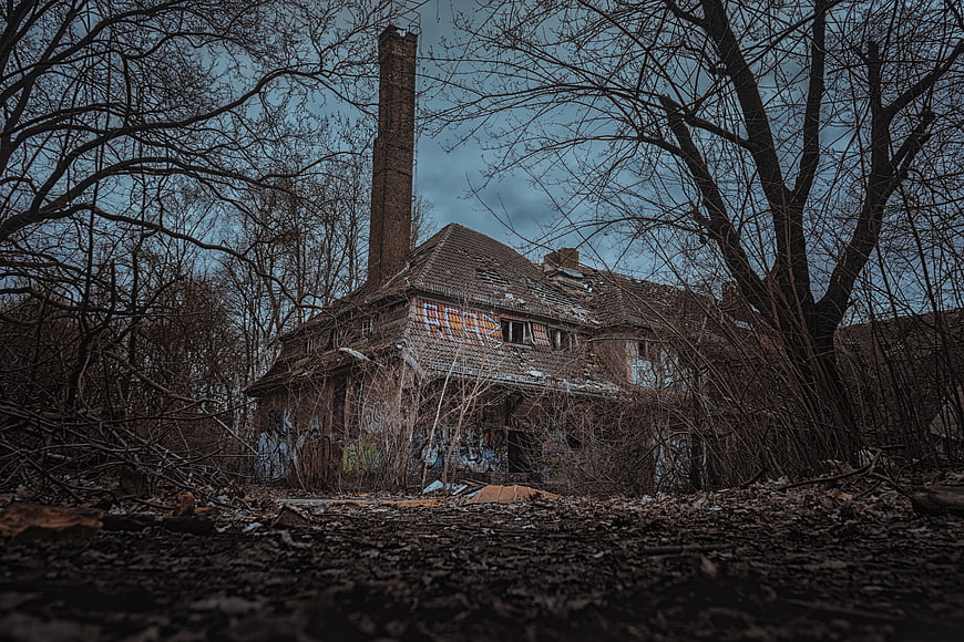 Abandoned industrial building with brick chimney and overgrown ruins