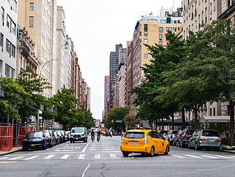 Yellow Taxi Driving on Manhattan Street with Cyclists