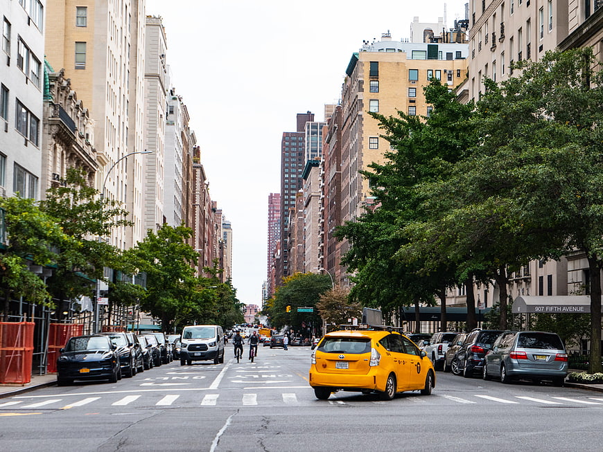 Yellow Taxi Driving on Manhattan Street with Cyclists