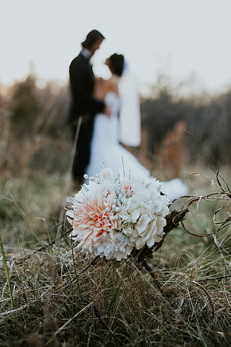 Wedding bouquet in grass with blurred couple background