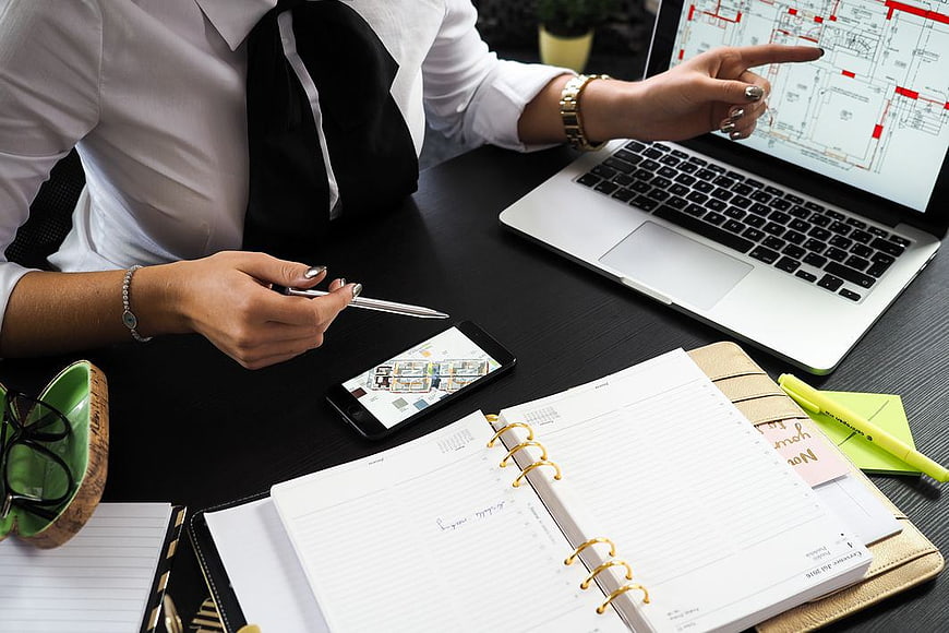 Businesswoman Reviewing Architectural Plans on Laptop