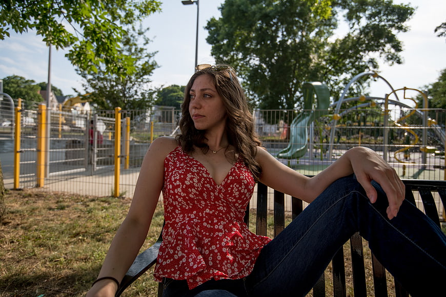 Young Woman Sitting on Park Bench Near Playground