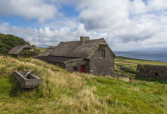 Traditional Irish stone cottage with thatched roof overlooking coastal landscape