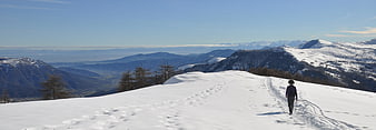 Lone Hiker Walking on Snowy Mountain Ridge with Panoramic View