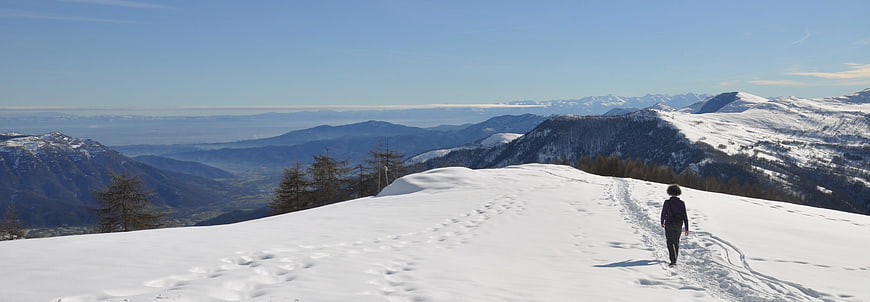 Lone Hiker Walking on Snowy Mountain Ridge with Panoramic View