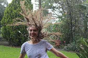 Happy woman shaking wet hair in the rain outdoors