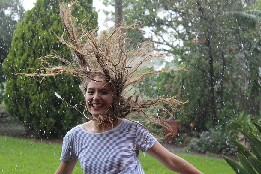 Happy woman shaking wet hair in the rain outdoors