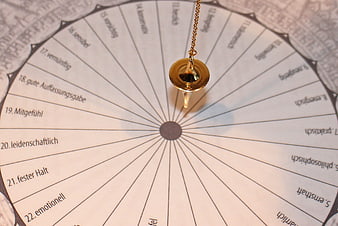 Gold pendulum over circular German esoteric chart