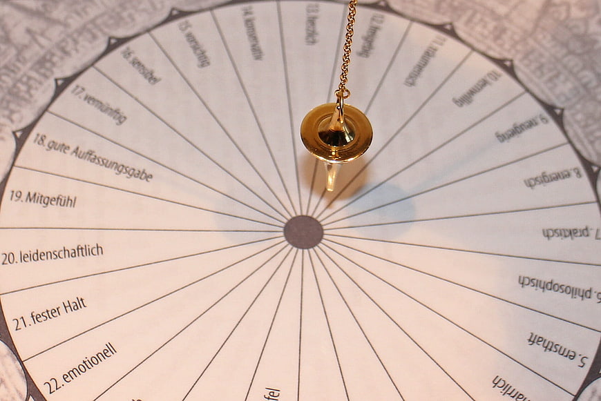 Gold pendulum over circular German esoteric chart