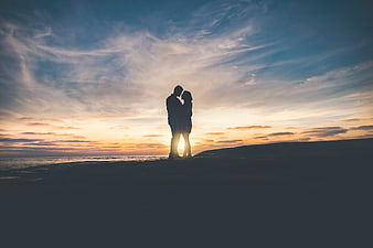 Silhouette of couple embracing on beach at sunset