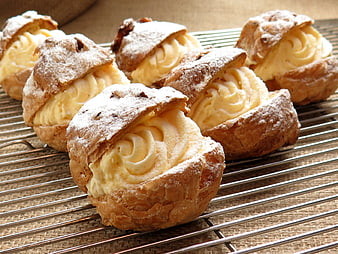 Cream-filled profiteroles on a wire cooling rack
