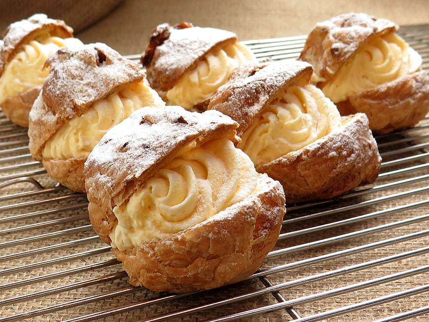 Cream-filled profiteroles on a wire cooling rack