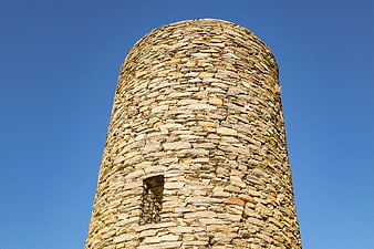 Low angle view of ancient stone tower against blue sky